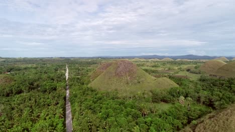 Aerial-view-road-crossing-the-Chocolate-Hills-Complex,-Batuan,-Philippines.