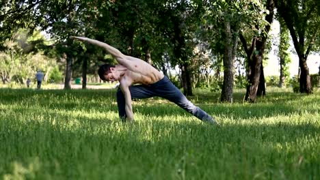 Schlanke-junge-Mann-praktizieren-Yoga-im-park