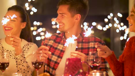 happy-friends-with-sparklers-having-christmas-dinner-at-home