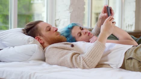 Joven-pareja-con-teléfono-móvil-acostado-en-cama