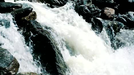 Schnelle-Gebirgsbach-fließt-aus-der-Gletscher-in-den-Bergen-Nahaufnahme.-Wasser-fließt-schnell-durch-die-Felsen-in-die-wilde,-Zeitlupe.