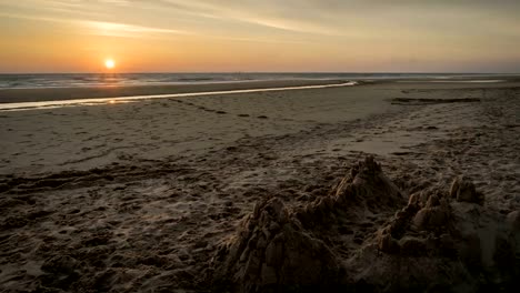 Zeitraffer-von-einem-Sonnenuntergang-am-Strand-von-Lacanau-mit-eine-Sandburg,-Frankreich