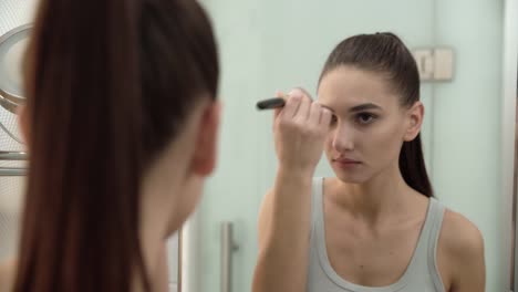 Maquillaje-de-la-cara.-Mujer-usando-polvo-y-mirando-en-el-espejo