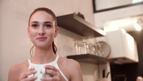 Joven-mujer-tomando-café-en-la-cocina-en-casa