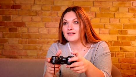 Close-up-shot-of-plump-housewife-playing-video-game-using-joystick-being-very-attentive-and-hipped-in-cozy-home.