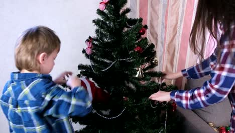 Mutter-und-Sohn-in-Weihnachtsmützen-schmücken-Weihnachtsbaum-mit-Perlen-und-Kugeln.