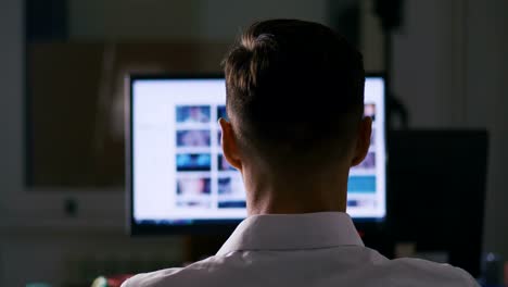 Back-view-Man-browsing-Internet-Sites-on-Computer-Monitor.-Web-Pages-Surfing,-Concept-of-searching-for-information-on-the-Internet.