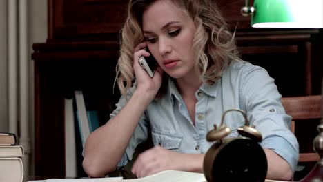 Worried-woman-talking-on-the-phone-sitting-at-her-workplace