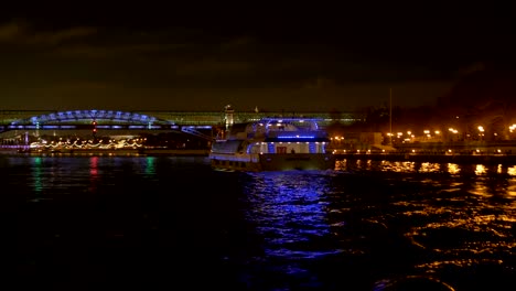 The-ship,-adorned-with-lights,-floats-along-the-river.