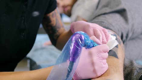 Female-tattoo-artist-with-pink-hair-making-tattoo-in-studio