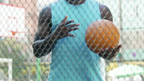 Sportsman-performing-set-of-exercises-on-sports-ground-before-basketball-game