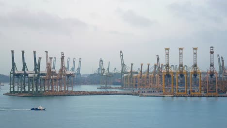 4K.-Singapore-shipping-port-with-cargo-ship-sailing-slowly-on-the-sea-and-many-container-and-yellow-cranes-in-background