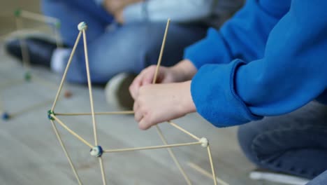 Manos-de-niña-construir-la-casa-modelo-con-palillos-de-madera