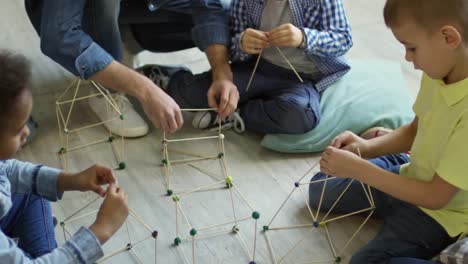 Kinder-machen-Häuser-aus-Holzstäbchen-mit-Hilfe-des-Lehrers