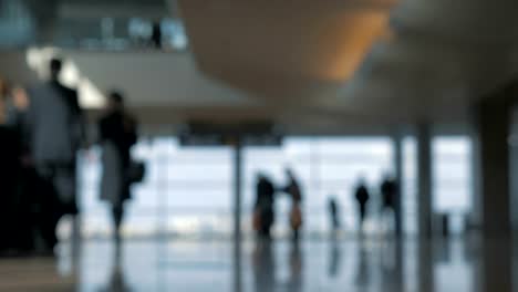 Airport-terminal-with-walking-people,-defocus