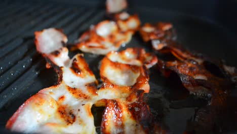 Close-up-of-a-slice-of-bacon-fried-on-a-hot-grill.