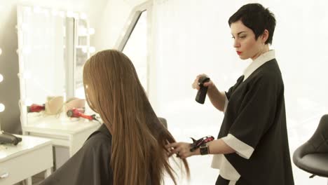 Friseur-Sprühwasser-auf-lange-Haare-weiblichen-Haarschnitt-im-Friseursalon.-Weibliche-Frisur-im-Beauty-Salon.-Haarschneider-mit-Kunden-arbeiten-hautnah