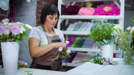 Professional-florist-clearing-and-inspecting-white-rose-branch-from-dry-petals