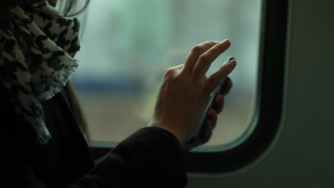 Nahaufnahme-der-Frau-mit-Smartphone-Gerät-beim-Pendeln-mit-dem-Zug.-Person-im-Internet-Surfen-und-e-Mails-im-Verkehr