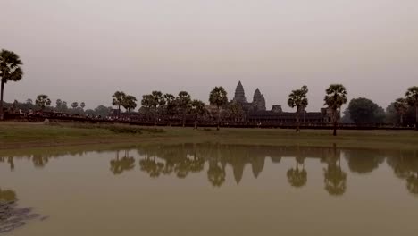 Kamerafahrt-in-Angkor-Wat-Tempel-bei-Sonnenaufgang-mit-Massen-von-Menschen-betreten-der-Anlage-auf-der-Seite