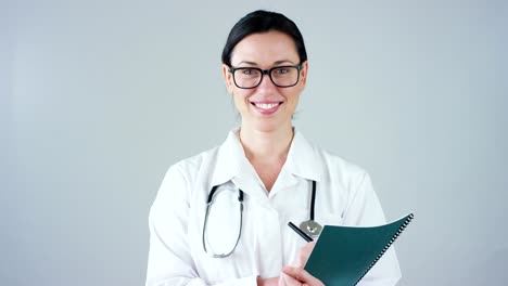 Portrait-of-a-female-doctor-with-white-coat-and-stethoscope-smiling-looking-into-camera-on-white-background.