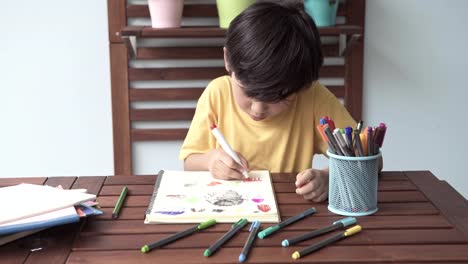 Kinder-Hausaufgaben.-Junge-Mischlinge-junge-Hausaufgaben-auf-der-Terrasse-zu-Hause.-Zeichnen-und-schreiben.-Fokus-Stimmung.-Zurück-zum-Schulkonzept.