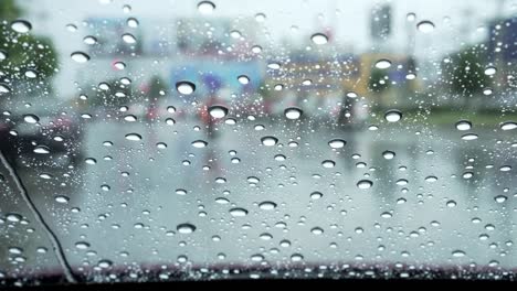 Car-windshield-with-rain-drops-during-heavy-traffic-downtown