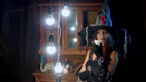 Halloween-Hexe-mit-Hut-hält-eine-Kerze-in-der-Hand-und-gießt-es.-Kerze-raucht
