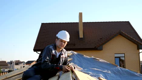 Adult-professional-builder-in-hardhat-measuring-length-of-wood-lumber-on-site-under-blue-sky