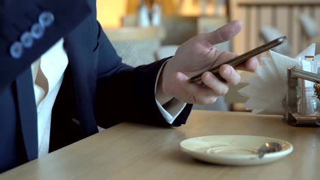 Young-man-with-a-phone-in-a-cafe.-Close-up