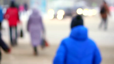 Boy-teenager-in-a-blue-down-jacket-standing-on-the-street.-On-the-background-of-the-ride-cars,-the-boy-turns-and-crosses-the-road.