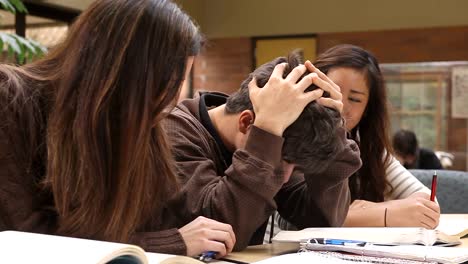 College-Studenten-studieren-Kursmaterial-in-einer-Gruppe-an-einem-Tisch-mit-Büchern-gefüllt