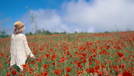 Mature-woman-enjoying-the-beauty-of-nature-on-a-colorful-poppy-field