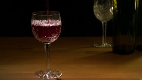 Rotwein-wird-in-ein-Glas-gegossen.