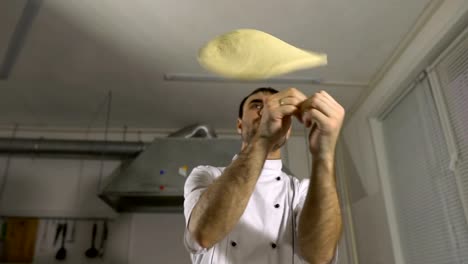 Cook-in-the-kitchen-preparing-pizza-dough,-juggling-them-with-his-hands