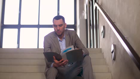 businessman-with-folder-sitting-on-stairs