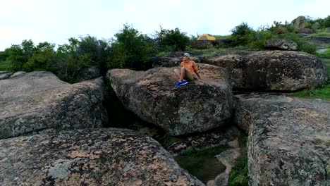 Junger-Mann-sitzt-auf-einem-Felsen