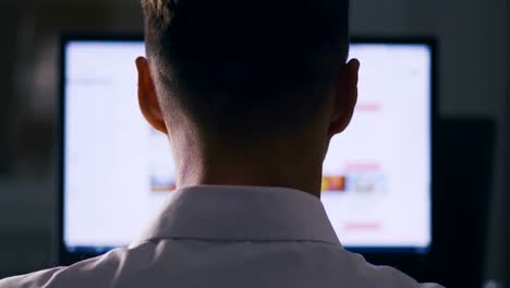 Back-view-Man-browsing-Internet-Sites-on-Computer-Monitor.-Web-Pages-Surfing,-Concept-of-searching-for-information-on-the-Internet.