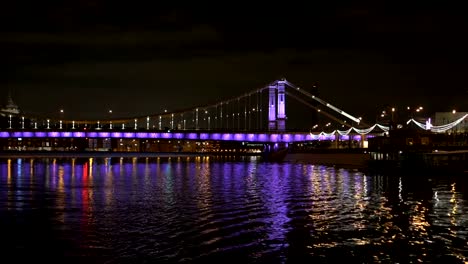 The-ship-sails-across-Moscow-river,-beautiful-reflection-of-the-bridge.-In-evening-time.