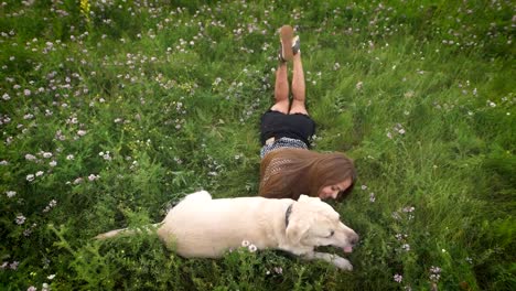 Schöne-Frau-Besitzer-liegen-auf-dem-Rasen,-liebkosen-und-streicheln-ihren-Labrador-Hund