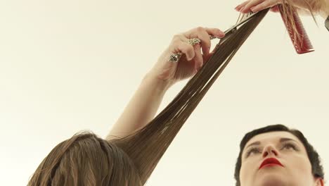 Haircutter-cutting-long-hair-with-hairdressing-scissors-in-beauty-salon.-Close-up-hairdresser-making-woman-haircut-with-scissors-in-hairdressing-salon