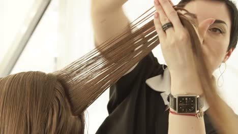 Hairstylist-combing-and-cutting-woman-hair-with-professional-scissors-in-hairdressing-salon.-Close-up-hairdresser-making-woman-haircut-with-scissors-in-beauty-salon