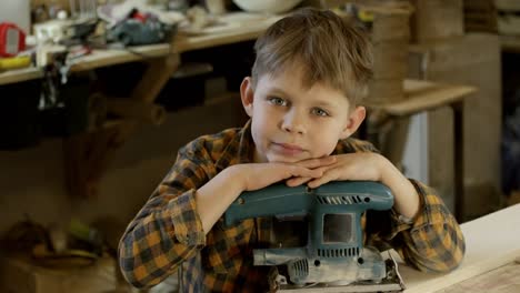 Boy-with-Belt-Sander-Posing-in-Workshop