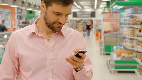 Cheerful-man-using-mobile-phone-in-shopping-mall