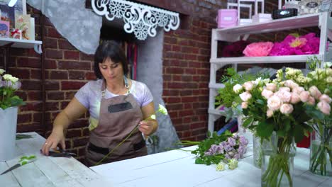 Dolly-shot-professional-florist-sorting-and-inspecting-white-rose-branch-from-dry-petals