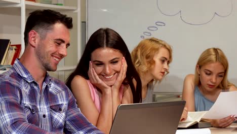 Two-young-cheerful-students-discussing-their-project-on-the-laptop