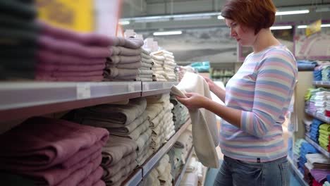 Kaukasischen-Frau-in-der-Nähe-von-Regalen-Handtuch-im-Store-auswählen