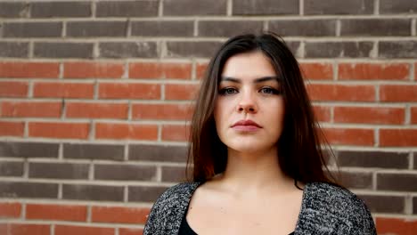 Portrait-of-a-young-confident-woman-against-a-brick-wall.-Slow-motion-shot.