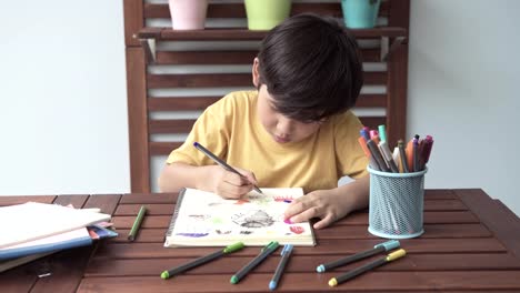 Kinder-Hausaufgaben.-Junge-Mischlinge-junge-Hausaufgaben-auf-der-Terrasse-zu-Hause.-Zeichnen-und-schreiben.-Fokus-Stimmung.-Zurück-zum-Schulkonzept.