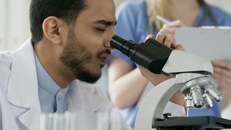 Científico-hombre-negro-usando-microscopio